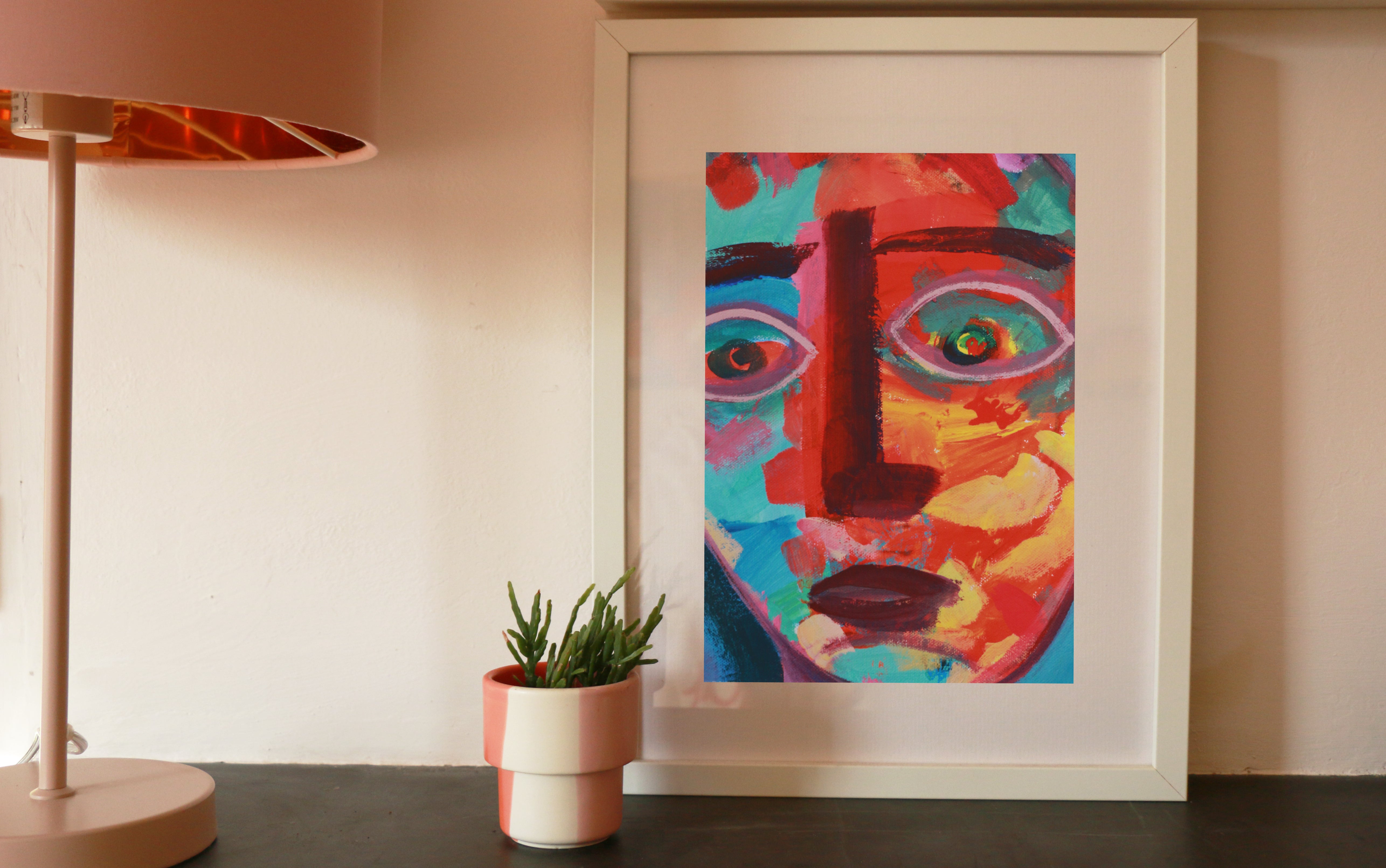 An image of a colourful face, framed and standing on a mantelpiece.